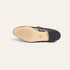 A single dark brown leather shoe shown from the sole side, featuring a beige insole with tread details and a black heel, photographed on a light cream background.