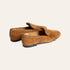 A pair of tan suede tassel loafers shown from a three-quarters angle on a light cream background.